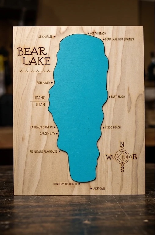 Bear Lake map on poplar: a turquoise lake inlay with engraved landmarks, the Idaho–Utah line and a compass rose